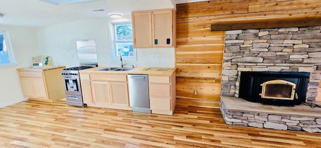 kitchen with sink, stainless steel appliances, light hardwood / wood-style floors, and wood walls