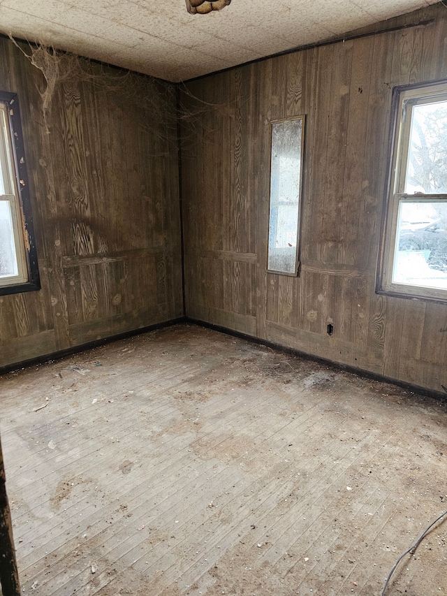 unfurnished room featuring hardwood / wood-style flooring, a healthy amount of sunlight, and wooden walls