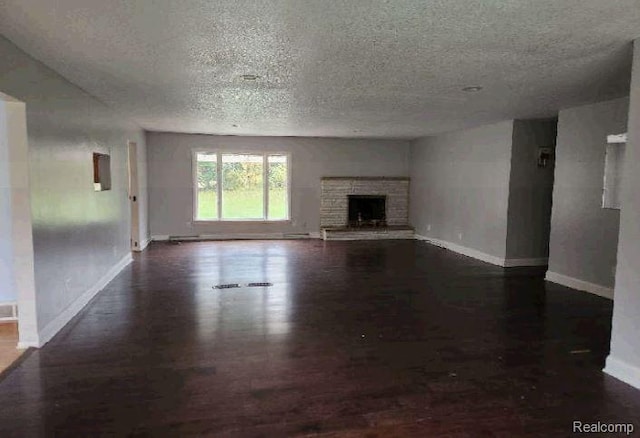 1080 Dye Krest Dr, Flint, MI 48532 - unfurnished living room featuring a textured ceiling, dark wood-style floors, and a stone fireplace
