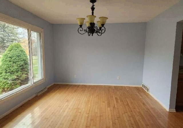 unfurnished room with light hardwood / wood-style flooring, an inviting chandelier, and plenty of natural light