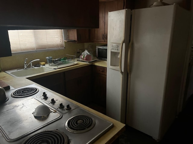 kitchen featuring sink, white refrigerator with ice dispenser, and range