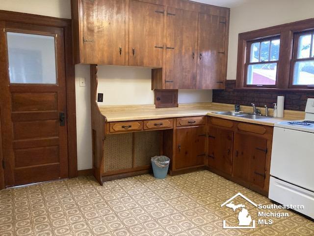 kitchen featuring stove, tasteful backsplash, and sink