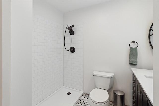 bathroom featuring toilet, vanity, and tiled shower