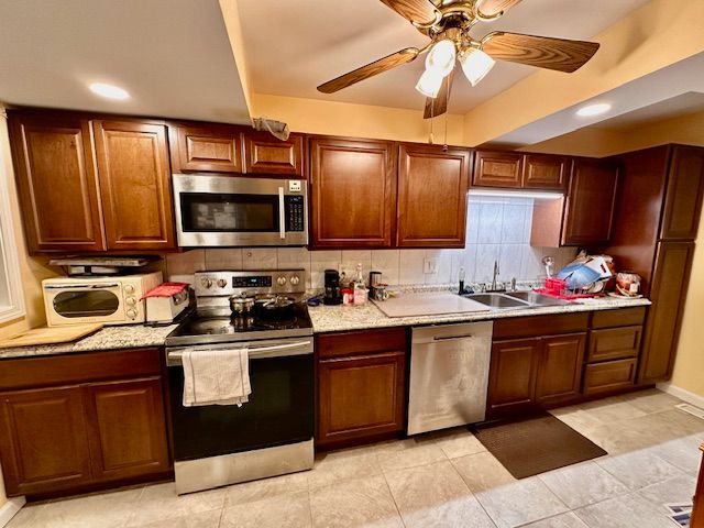 kitchen with sink, ceiling fan, light tile patterned floors, tasteful backsplash, and stainless steel appliances