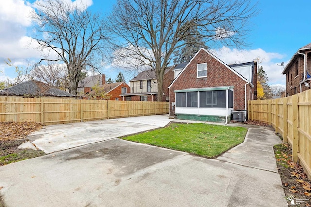 back of property featuring a lawn, a sunroom, and cooling unit