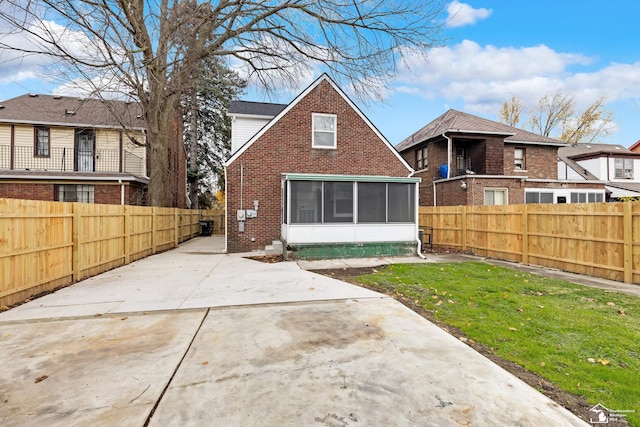 back of property with a lawn and a sunroom