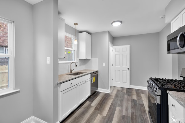 kitchen featuring white cabinets, appliances with stainless steel finishes, hanging light fixtures, and sink