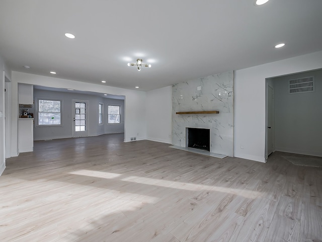 unfurnished living room featuring light wood-type flooring and a high end fireplace