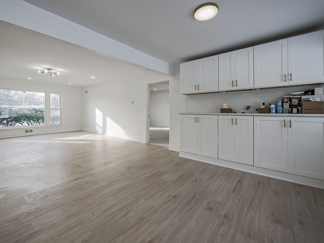 kitchen with white cabinetry, light wood-type flooring, and decorative backsplash