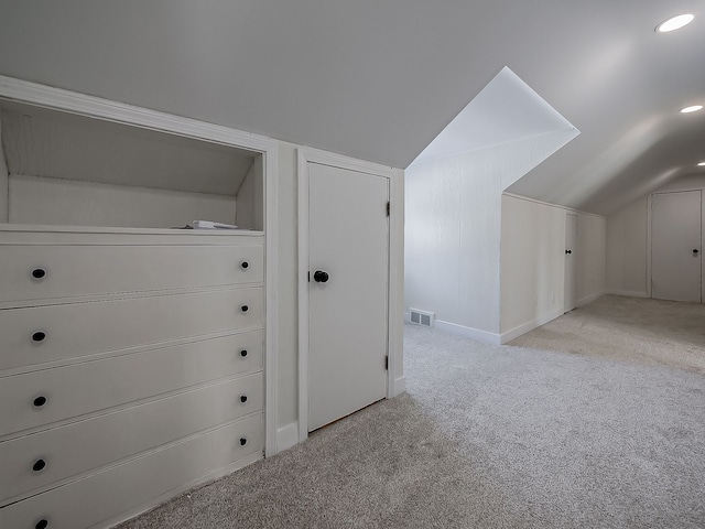 additional living space featuring light colored carpet and vaulted ceiling