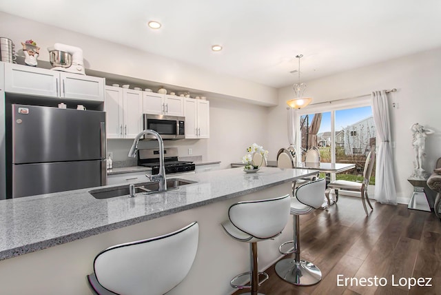 kitchen featuring light stone countertops, dark hardwood / wood-style floors, decorative light fixtures, white cabinets, and appliances with stainless steel finishes