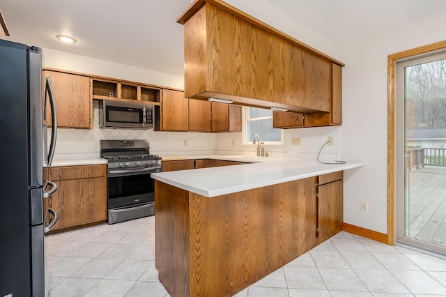 kitchen featuring backsplash, sink, light tile patterned floors, appliances with stainless steel finishes, and kitchen peninsula