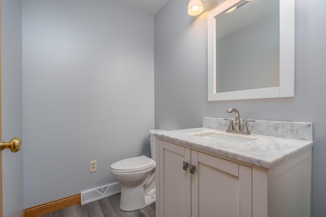 bathroom with vanity, toilet, and wood-type flooring