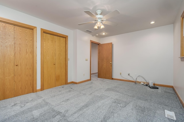 unfurnished bedroom featuring multiple closets, ceiling fan, and light carpet