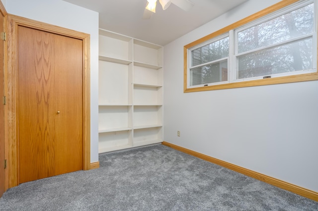 unfurnished bedroom with a closet, dark carpet, and ceiling fan