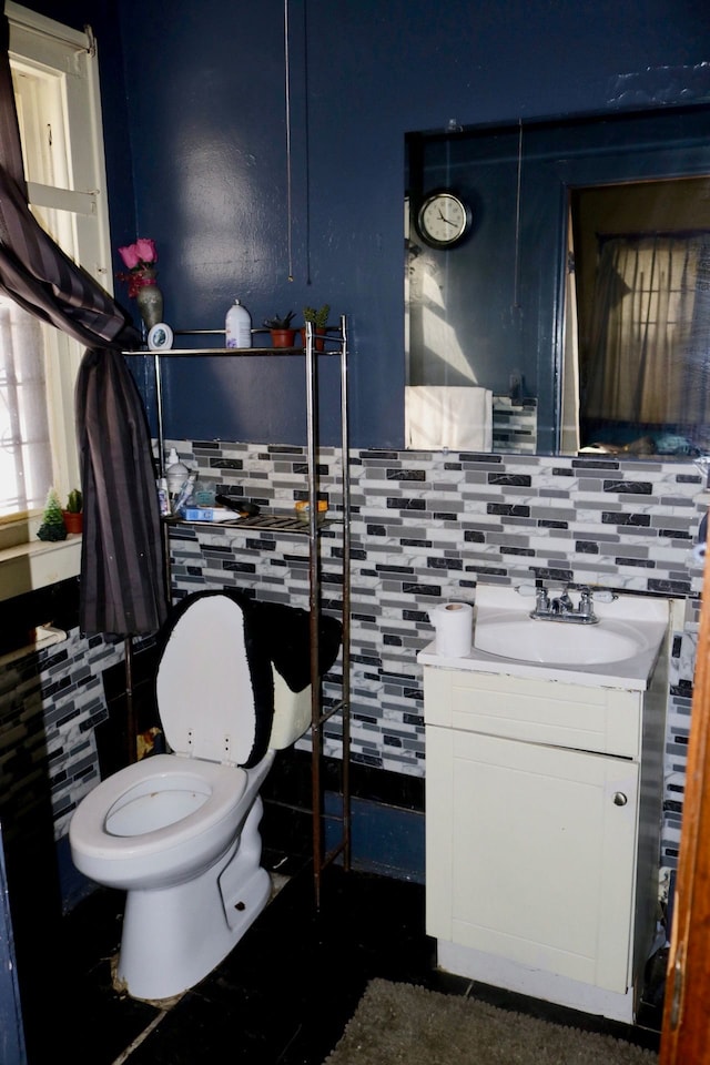 bathroom with toilet, vanity, and tasteful backsplash