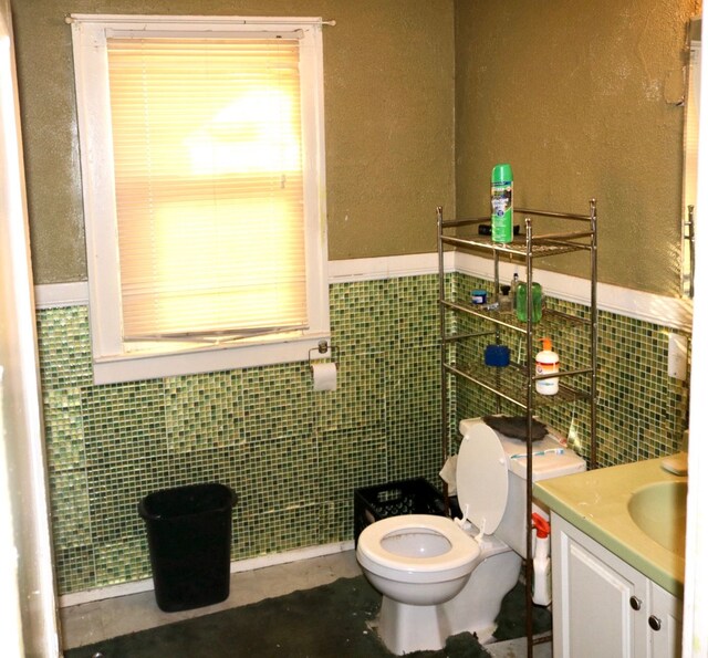 bathroom featuring tile walls, toilet, and vanity