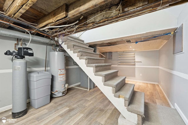 basement featuring hardwood / wood-style flooring and water heater