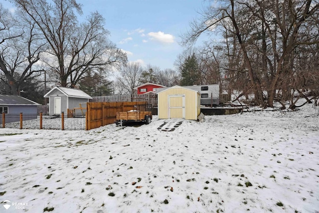 yard covered in snow with a wooden deck and a storage unit