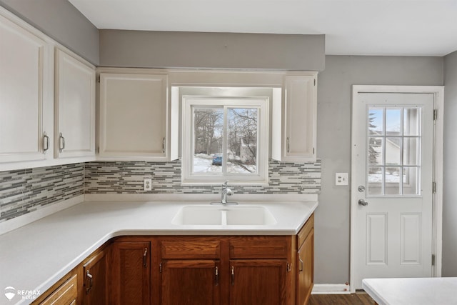 kitchen with decorative backsplash, white cabinetry, and sink