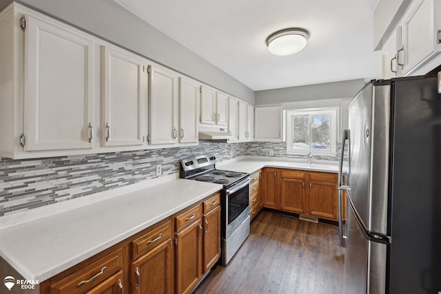 kitchen featuring decorative backsplash, dark hardwood / wood-style flooring, stainless steel appliances, sink, and white cabinetry