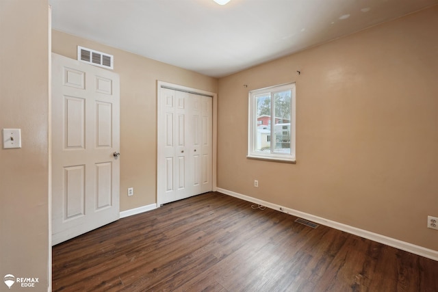 unfurnished bedroom with dark hardwood / wood-style floors and a closet