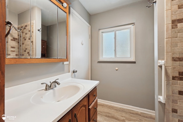 bathroom with a tile shower, vanity, and hardwood / wood-style flooring