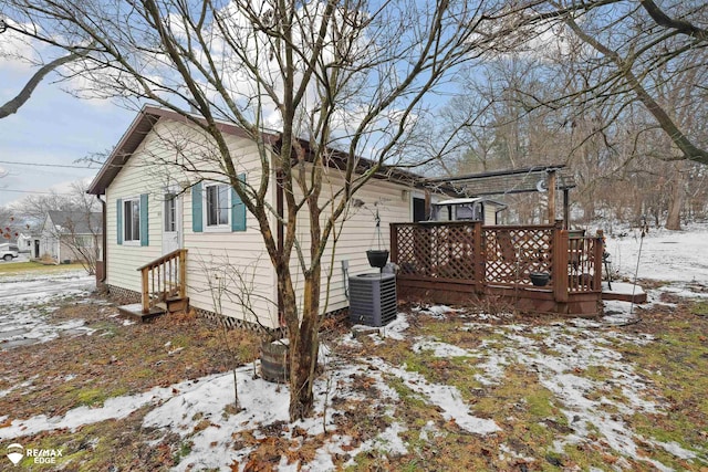 snow covered property with central AC and a wooden deck