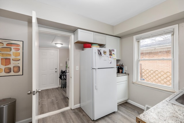 kitchen featuring white fridge, light wood-type flooring, and white cabinetry