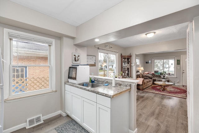 kitchen with light hardwood / wood-style flooring, white cabinetry, and sink