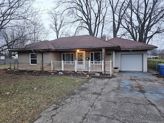 ranch-style home with a front lawn, a porch, and a garage