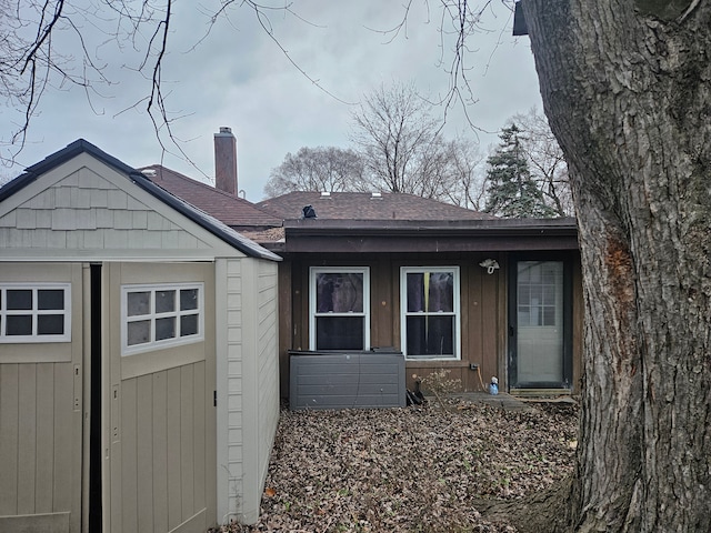 back of house with a storage unit