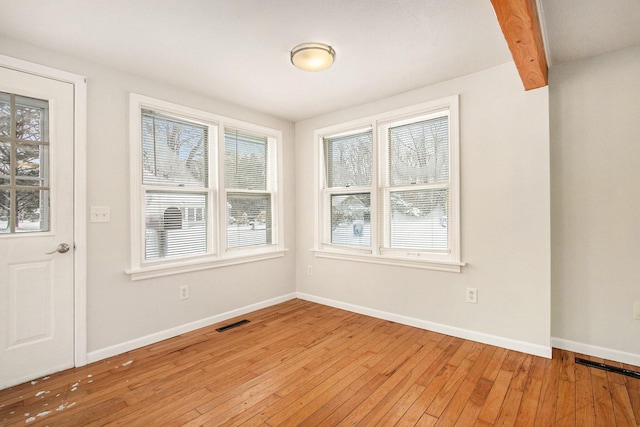 unfurnished dining area with beam ceiling and light hardwood / wood-style floors