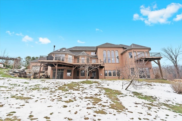 snow covered back of property with a balcony