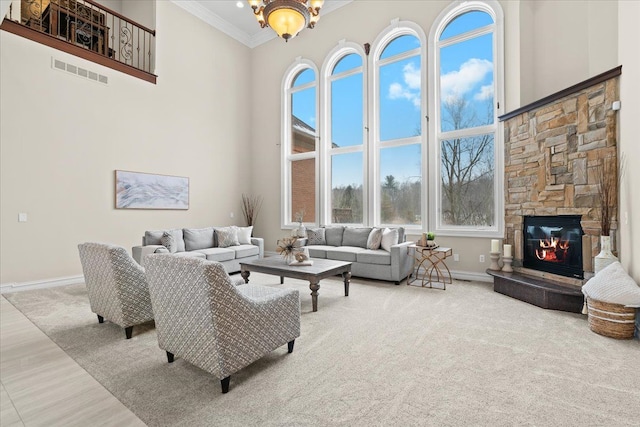 living room featuring a fireplace, a high ceiling, an inviting chandelier, and crown molding