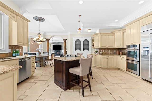 kitchen featuring light stone countertops, appliances with stainless steel finishes, tasteful backsplash, a breakfast bar, and pendant lighting