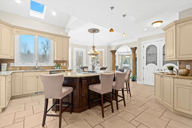 kitchen featuring a kitchen bar, tasteful backsplash, sink, pendant lighting, and a center island