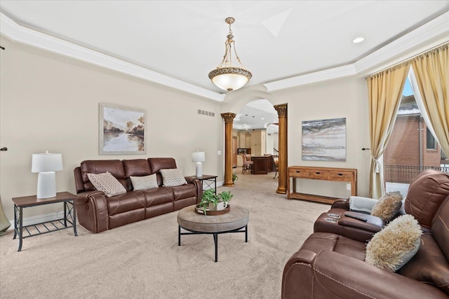 carpeted living room with a raised ceiling, a skylight, and decorative columns