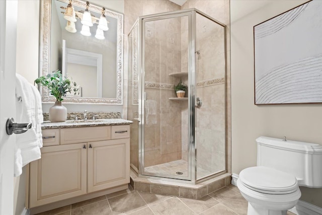 bathroom with tile patterned floors, vanity, a shower with shower door, and toilet