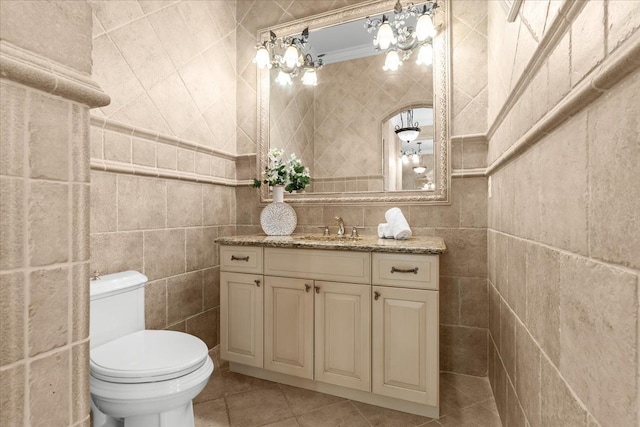 bathroom featuring tile patterned floors, crown molding, toilet, vanity, and tile walls