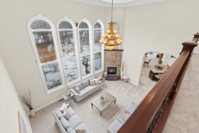 living room with light carpet, a fireplace, ornamental molding, and a notable chandelier