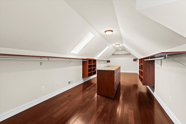 walk in closet with dark hardwood / wood-style flooring and vaulted ceiling with skylight