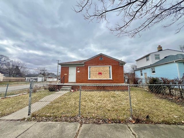 bungalow-style house with brick siding, a fenced front yard, and a front yard