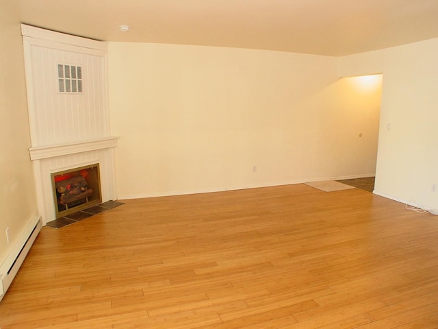 unfurnished living room with a fireplace, a baseboard radiator, and light hardwood / wood-style floors