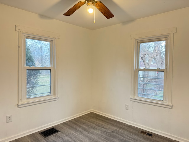 unfurnished room with a wealth of natural light, ceiling fan, and dark wood-type flooring