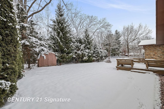 snowy yard featuring a storage shed