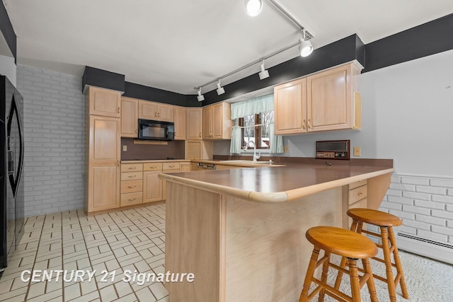 kitchen with a kitchen bar, sink, kitchen peninsula, and black appliances