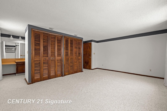 unfurnished bedroom featuring ensuite bath, light carpet, and a textured ceiling