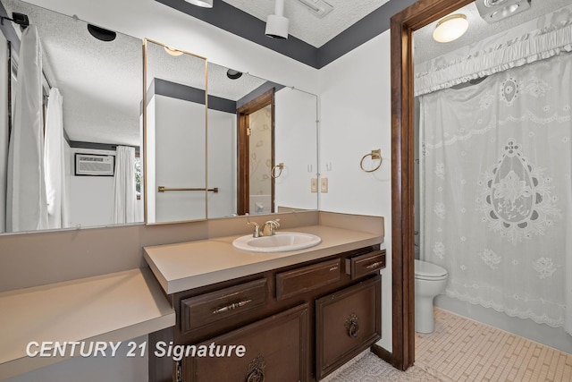 bathroom with vanity, tile patterned flooring, toilet, a textured ceiling, and a wall unit AC