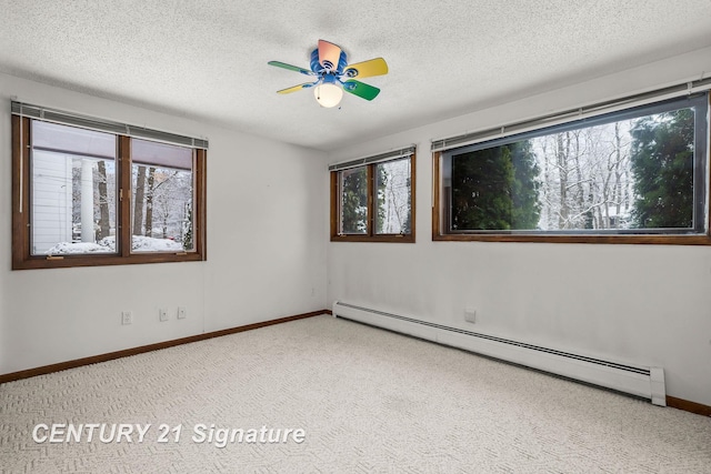 unfurnished room with a textured ceiling, a baseboard radiator, a wealth of natural light, and ceiling fan